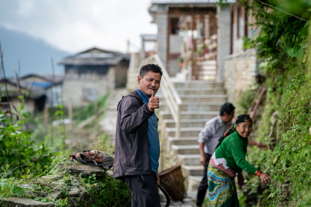 A local Nepali man gives the camera a thumbs up while he and his mother tend to their garden in Ghadruk, Nepal.