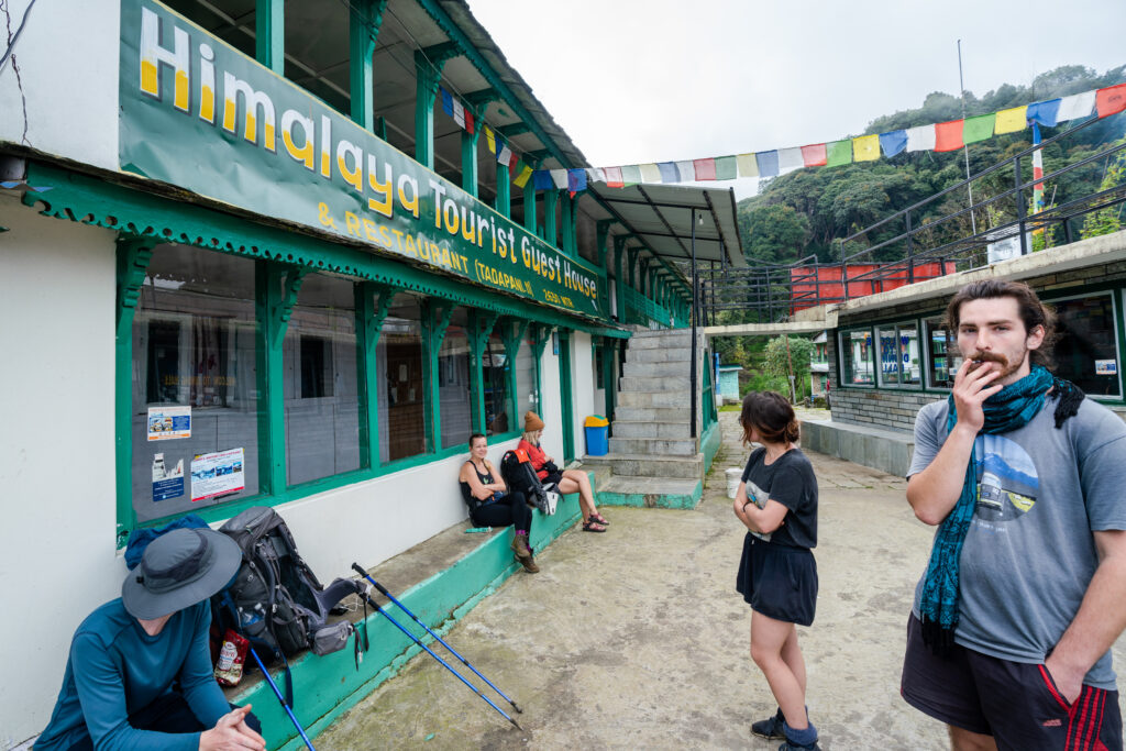 A group of trekkers hanging outside in the courtyard of a typical Nepali teahouse in the Himalayas.