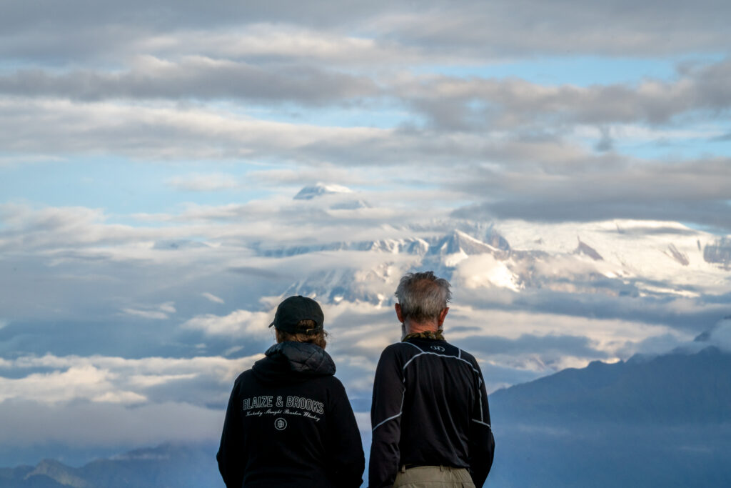 A woman and her father look at the views of the snowy Himalayas at the top of Poon Hill in Nepal.