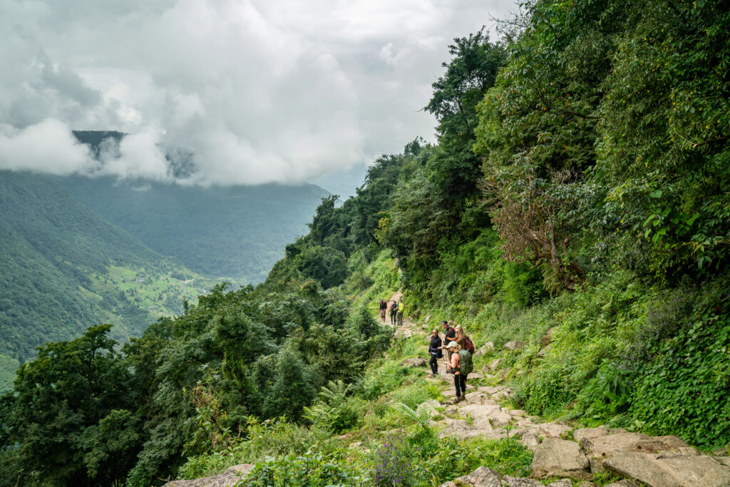 A group of trekkers on the trail in Nepal look out over a valley from their resting point on the trail.