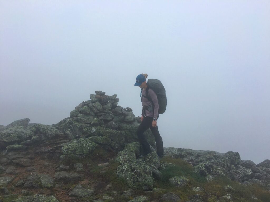 A woman hiking on Mt. Washington in Vermont while wearing waterproof Outdoor Research leg gaiters.