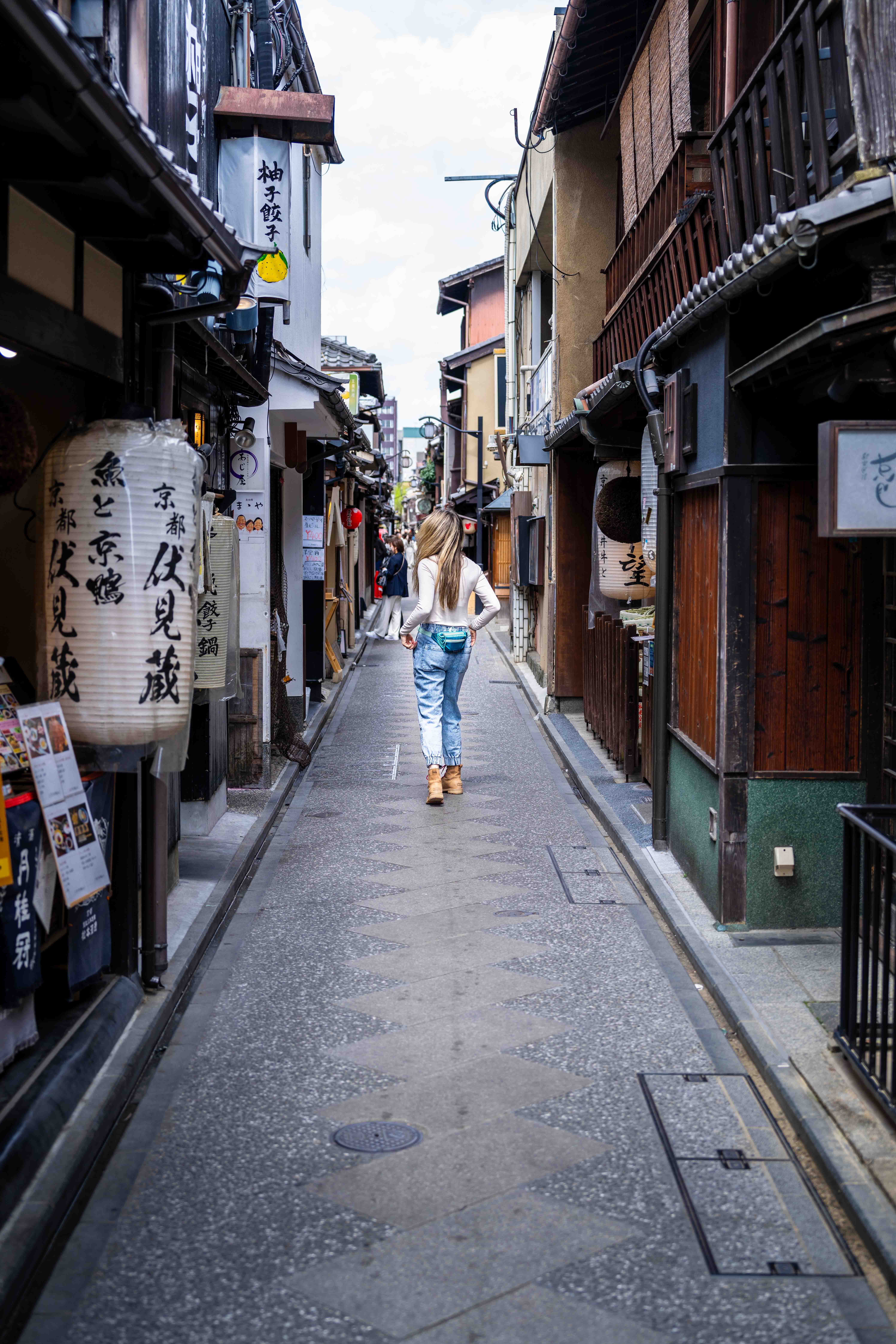 A woman walks down a tiny street in Kyoto, Japan.