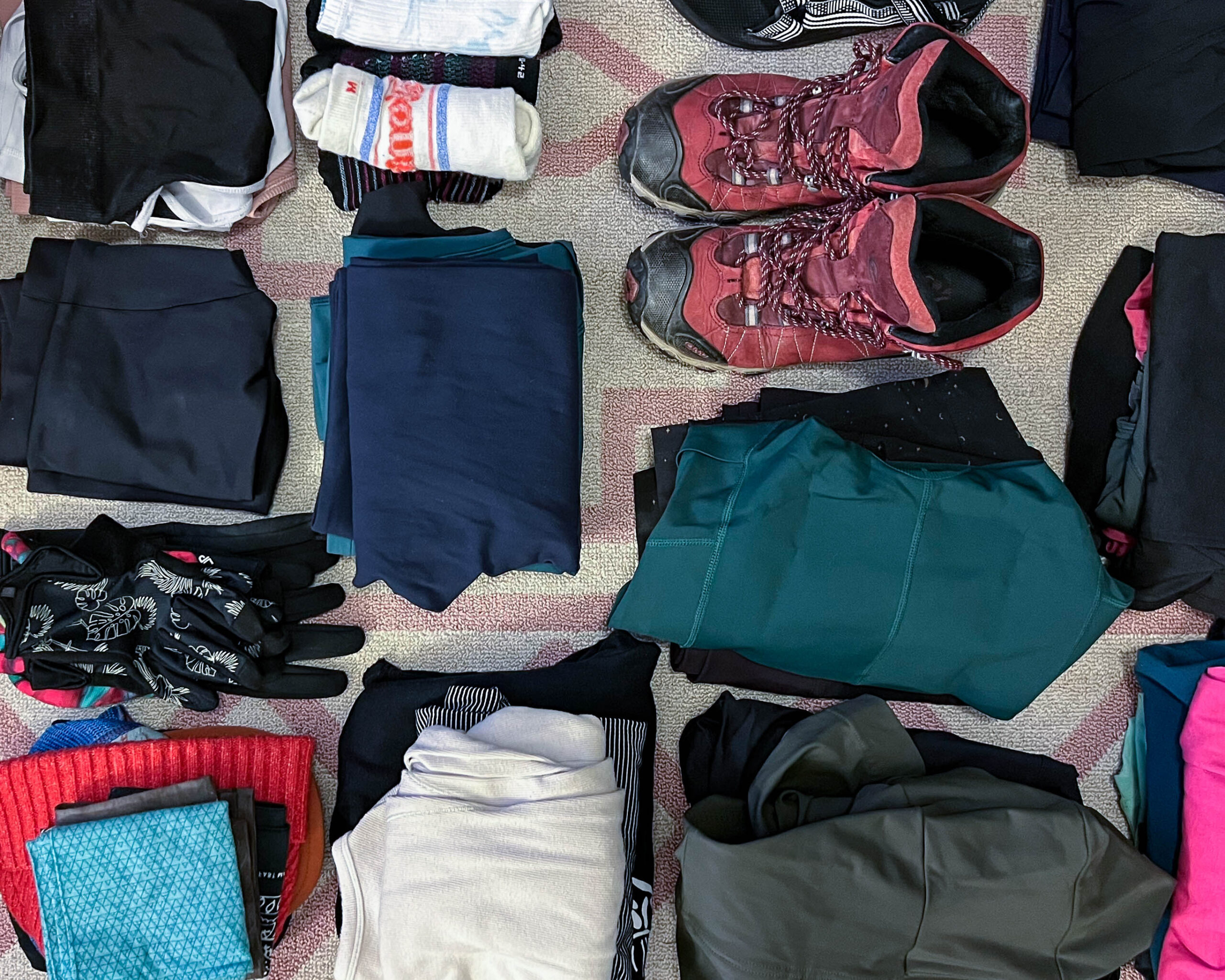 Clothes and shoes sitting on the floor are organized into piles for efficient packing.