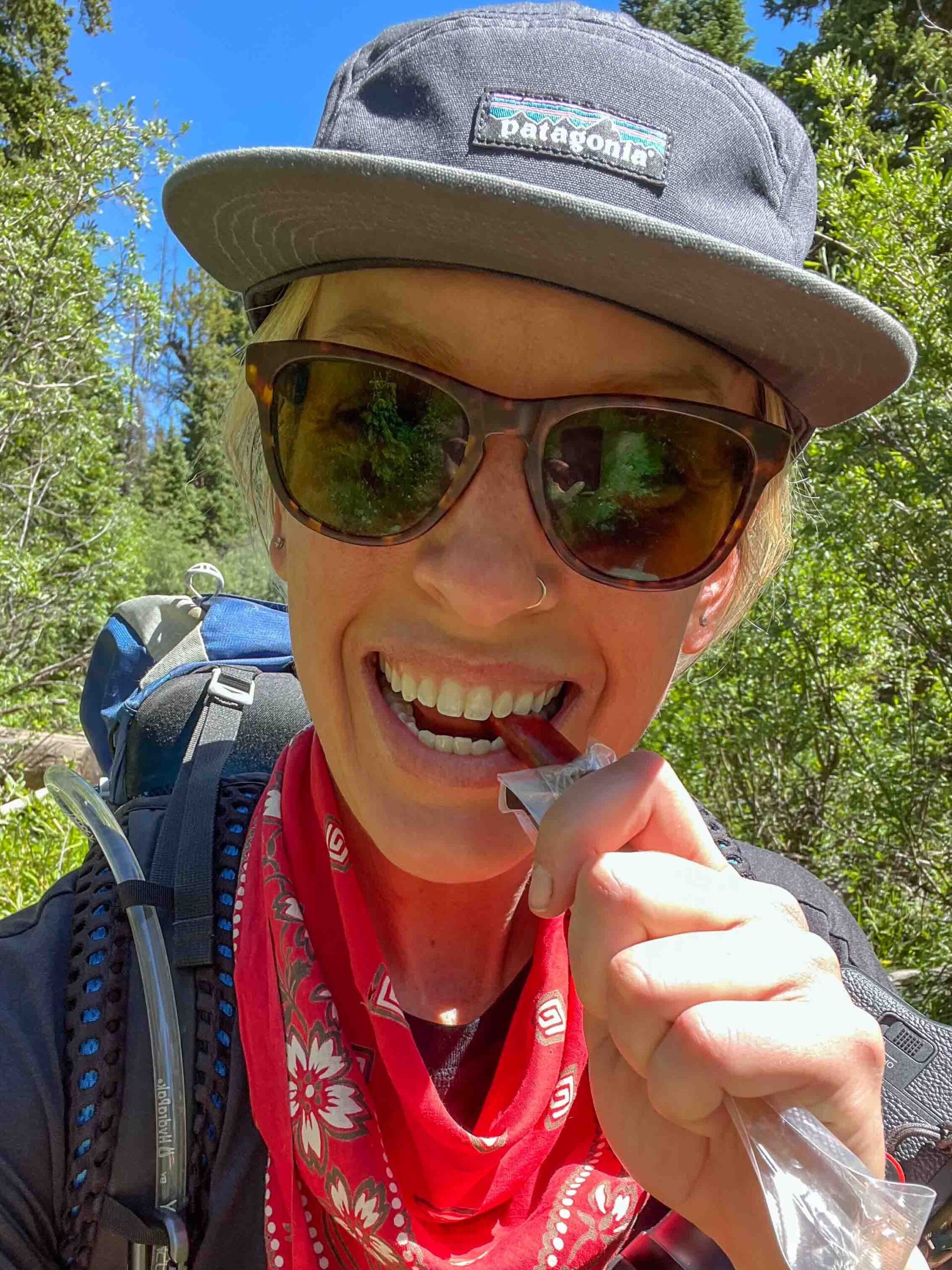 Hilary Lex bites into a beef stick while hiking on a trail in Colorado.