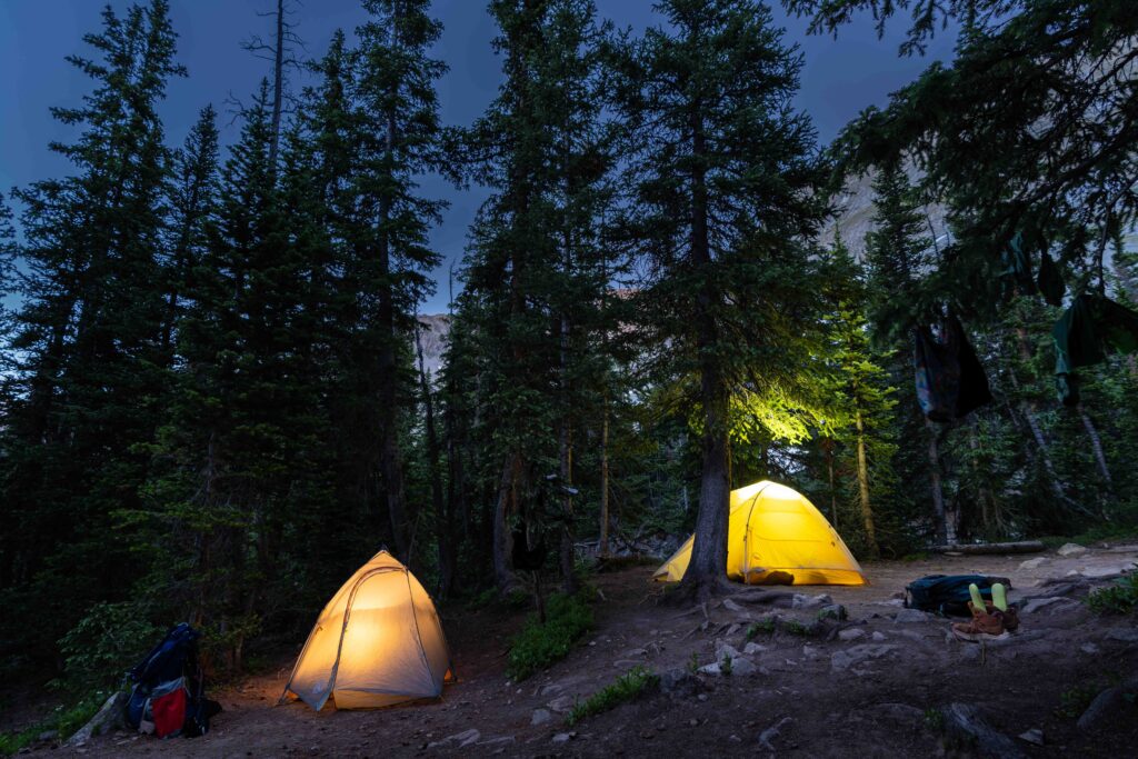 Two tents are lit up at night at a campsite at Conundrum Hot Springs in Colorado.