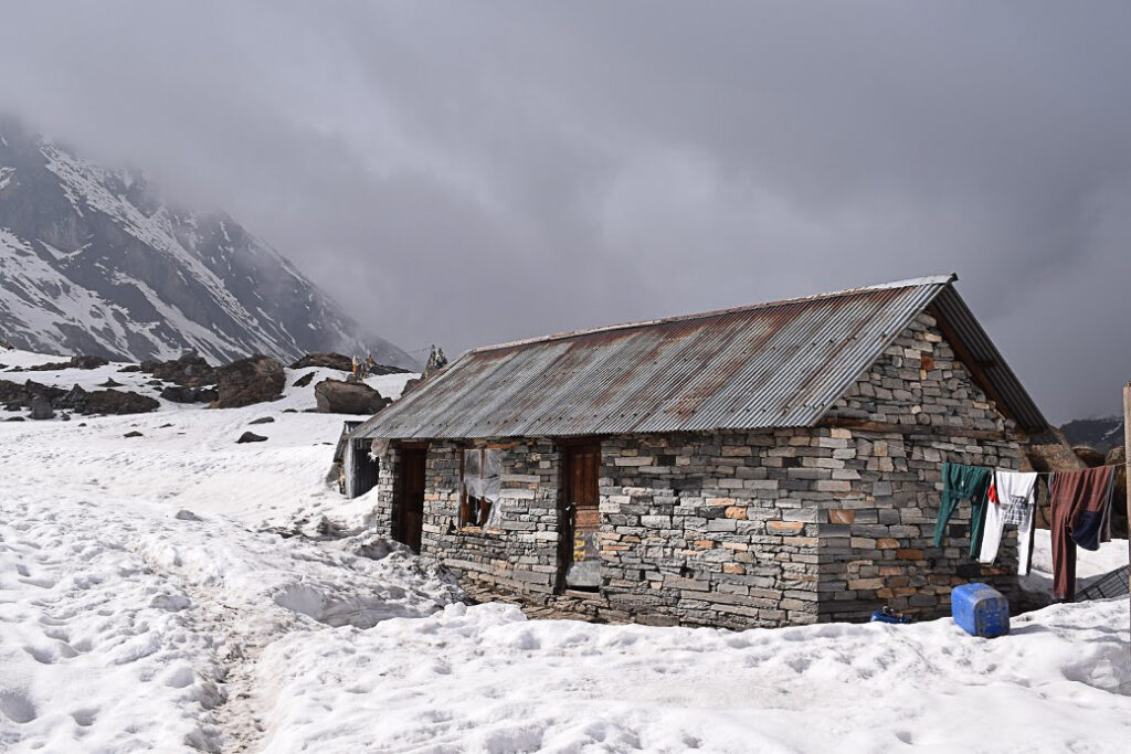 An old stone house with snow surrounding it at Annapurna Base Camp.