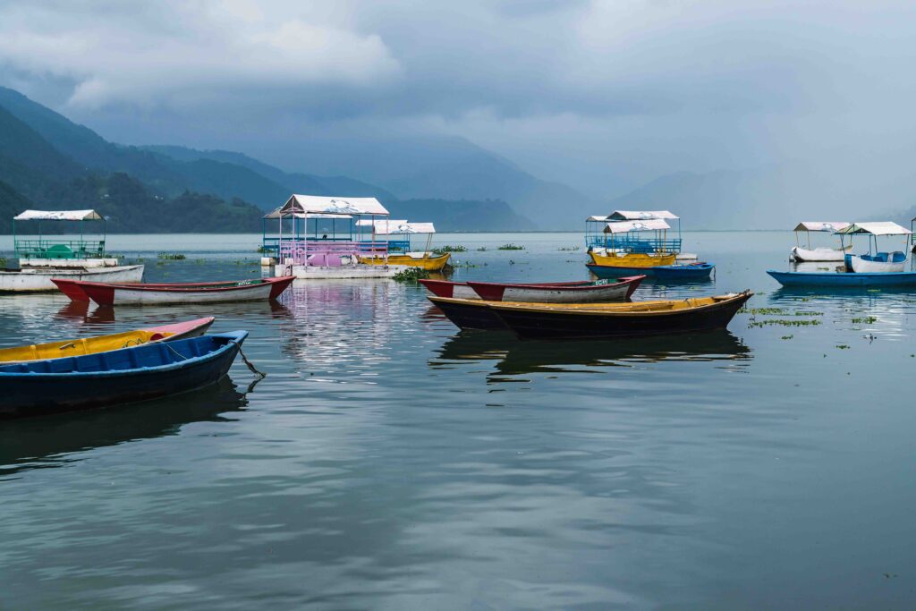 Boats floating on a calm Phewa Lake in Pokhara, Nepal on an overcast day.