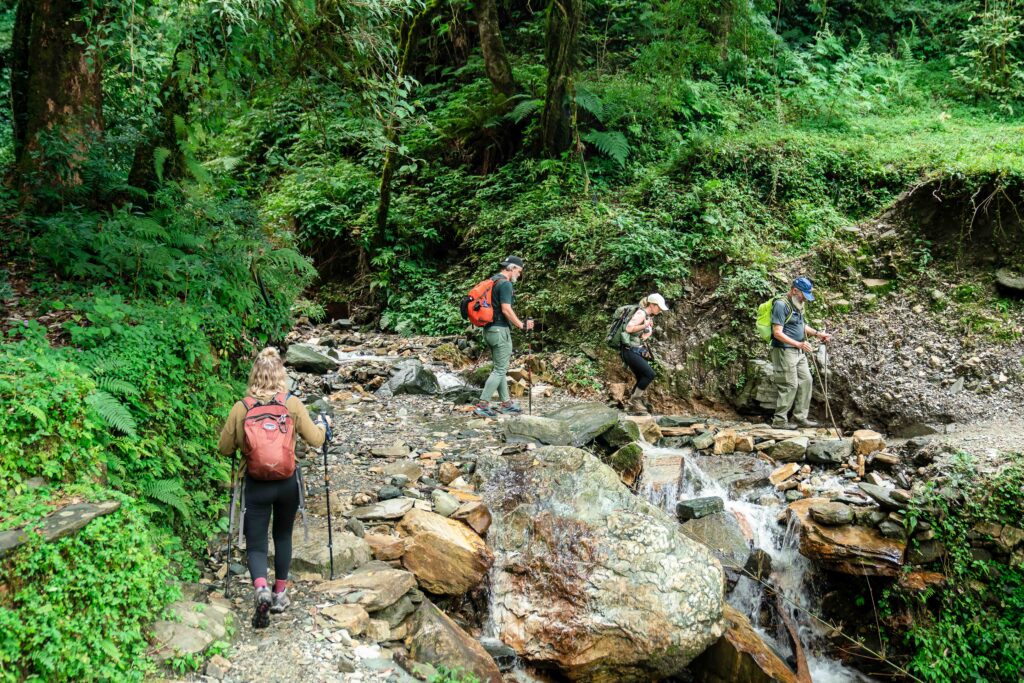 A group of trekkers walking across a small stream on the way to Poon Hill in Nepal.