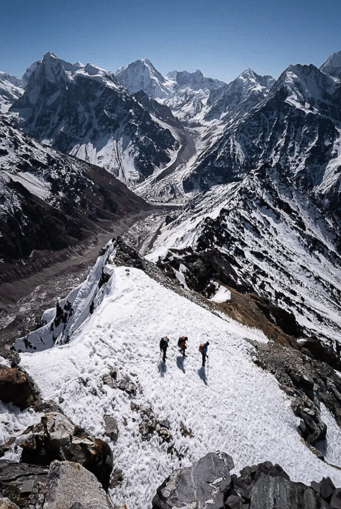 3 trekkers walking down from the Yala Peak summit in Langtang Valley in Nepal.