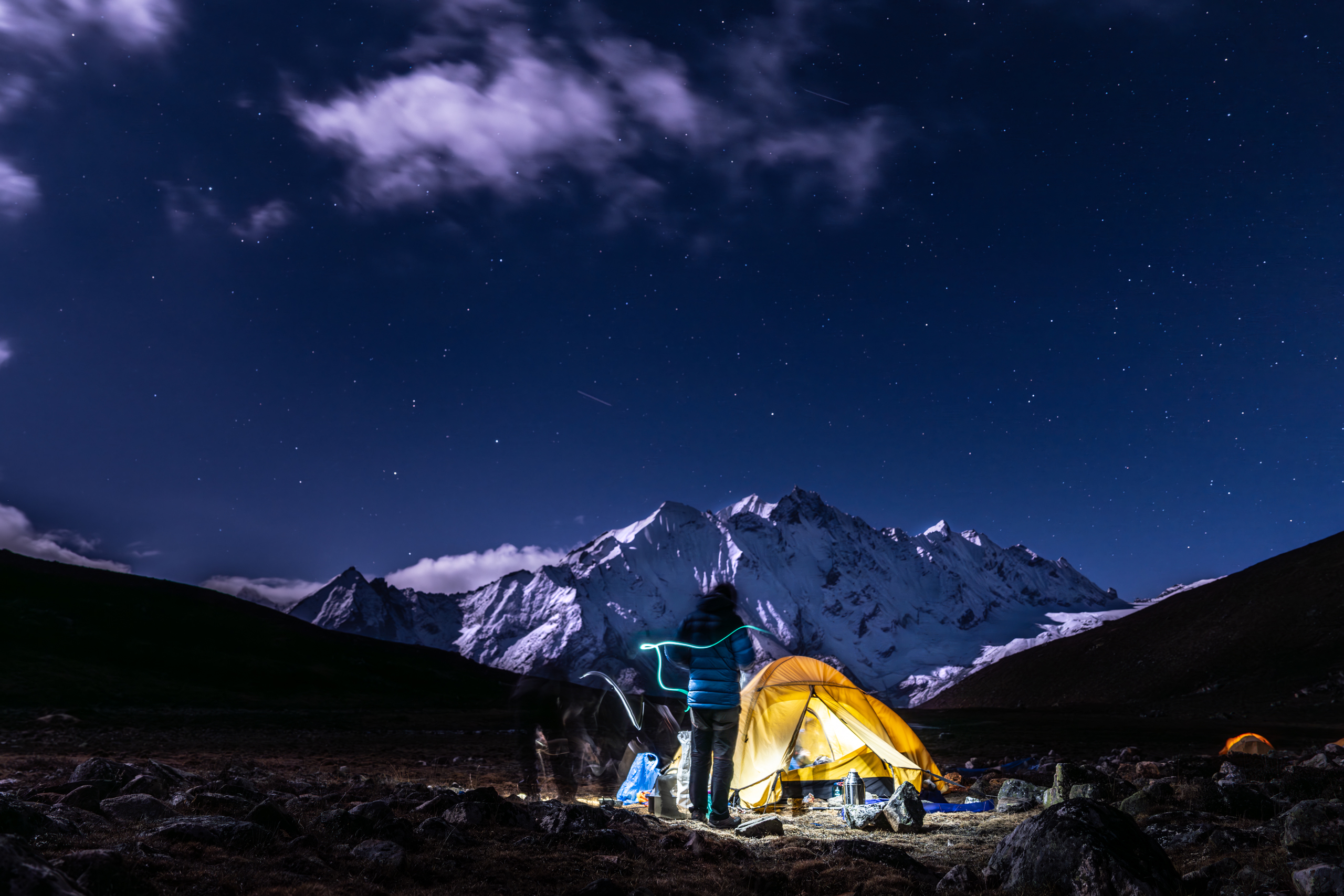 a campsite under a starry sky and below a snowcapped mountain peak in the himalayas at yala peak base camp in nepal